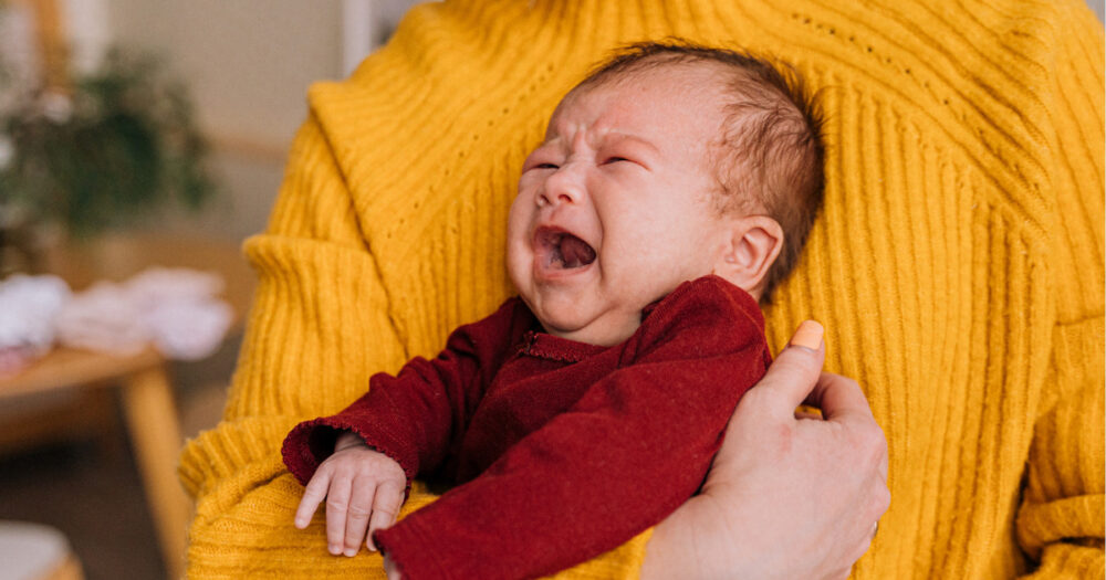 ママに抱きかかえられる泣いている赤ちゃん